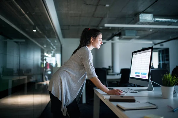 Junge Geschäftsfrau mit Computer steht in einem Büro und arbeitet. — Stockfoto