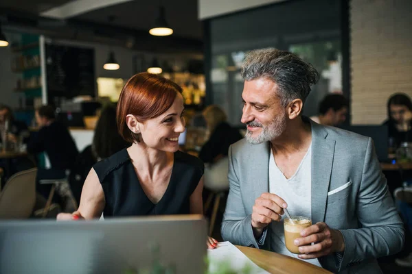 Homme et femme ayant une réunion d'affaires dans un café, en utilisant un ordinateur portable . — Photo