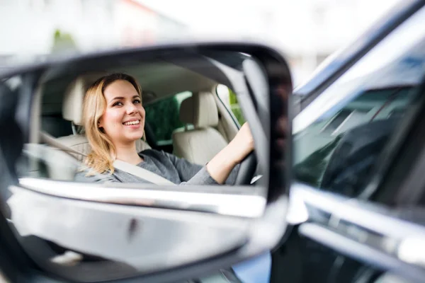 Mirror reflection of young woman driver sitting in car, driving. — Stock Photo, Image