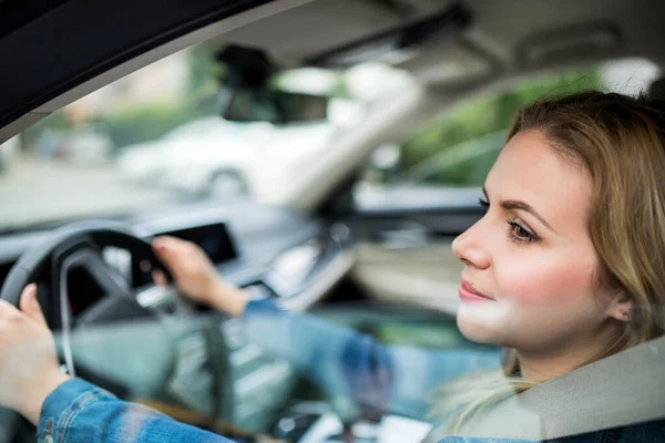 Ung kvinna förare sitter i bilen. Skjuten genom glas. — Stockfoto