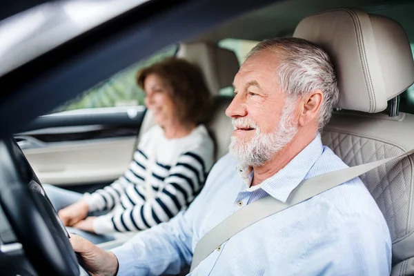 Feliz pareja de ancianos con teléfono inteligente sentado en el coche, conducción ,. — Foto de Stock