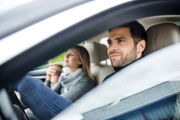 Glada unga par med kaffe sittande i bilen, körning. — Stockfoto