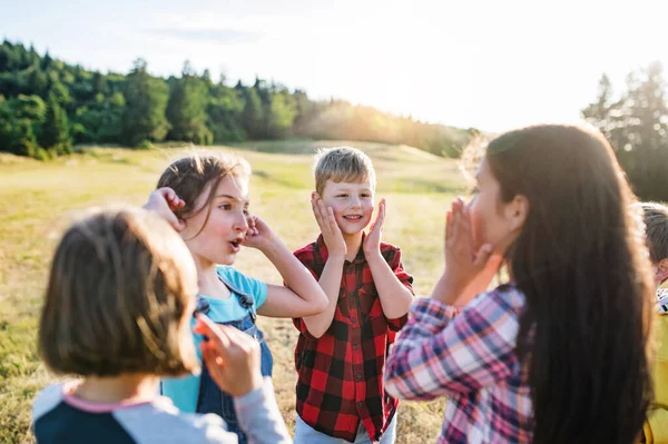 Group of school children standing on field trip in nature, playing. — Stock Photo, Image