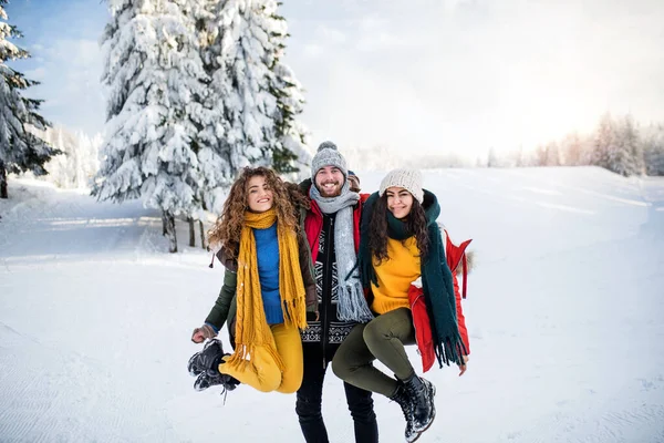 En grupp glada unga vänner som står utomhus i snön i vinterskogen. — Stockfoto