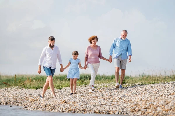 Familia multigeneracional en unas vacaciones caminando por el lago, tomados de la mano . — Foto de Stock