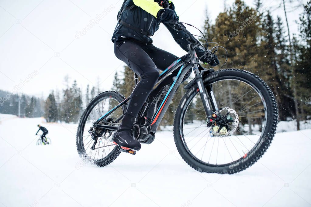 Midsection of mountain biker riding in snow outdoors in winter.