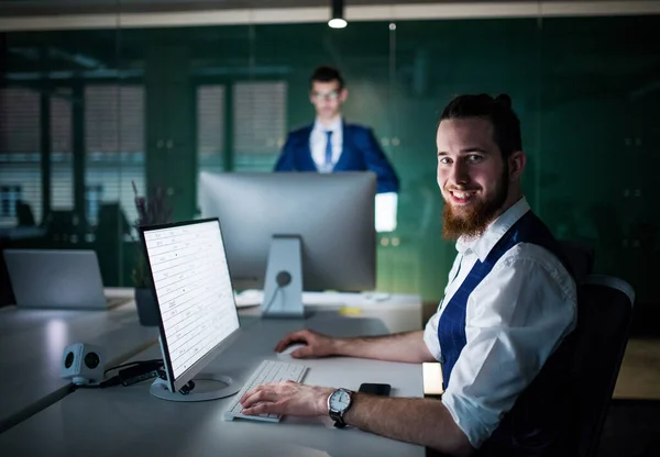 Ett porträtt av ung affärsman med laptop sitter på ett kontor. — Stockfoto
