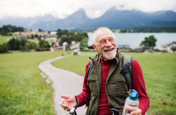 Homem sênior com pólos de caminhada nórdicos caminhadas na natureza, descansando . — Fotografia de Stock