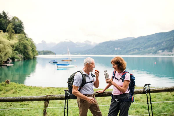 Rentnerehepaar mit Nordic-Walking-Stöcken wandert in der Natur, rastet aus. — Stockfoto