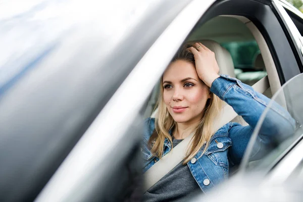 Młoda kobieta kierowca siedzi w samochodzie, czeka. — Zdjęcie stockowe