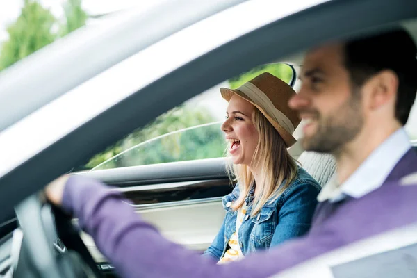 Feliz joven pareja sentada en el coche, hablando . —  Fotos de Stock