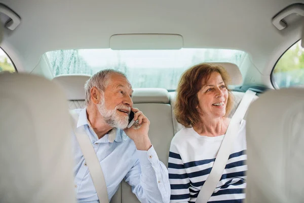 자동차에 앉아, 이야기 스마트 폰과 행복한 노인 부부. — 스톡 사진