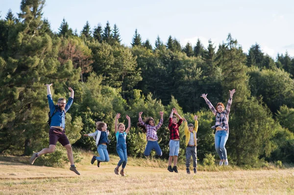 Groupe d'écoliers avec professeur en excursion dans la nature, saut . — Photo