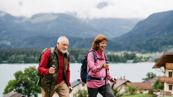Rentnerehepaar wandert mit Nordic-Walking-Stöcken in der Natur. — Stockfoto