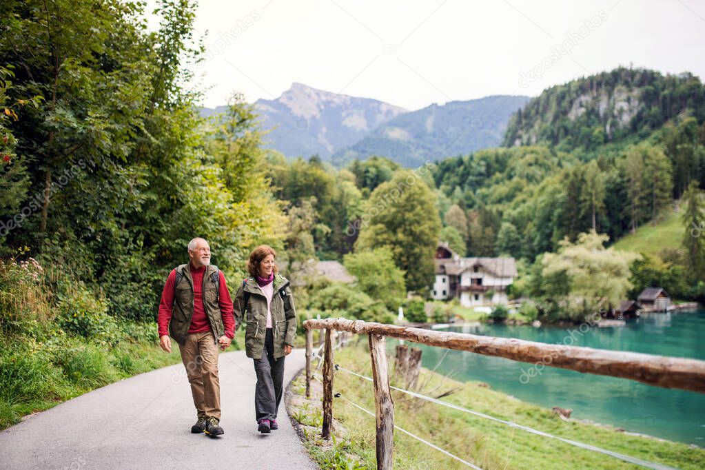 A senior pensioner couple hiking in nature, holding hands.