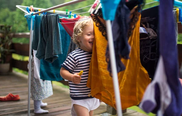 Bambini piccoli all'aperto in estate, giocando con appendiabiti asciugatura . — Foto Stock