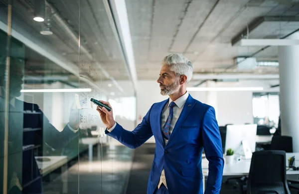 Πορτρέτο του ώριμου επιχειρηματία στέκεται σε ένα γραφείο, brainstorming. — Φωτογραφία Αρχείου