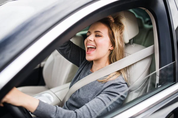 Glada ung kvinna förare sitter i bilen, körning. — Stockfoto