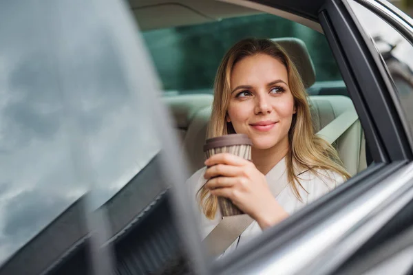 Mulher de negócios com café sentado em assentos traseiros em carro de táxi . — Fotografia de Stock