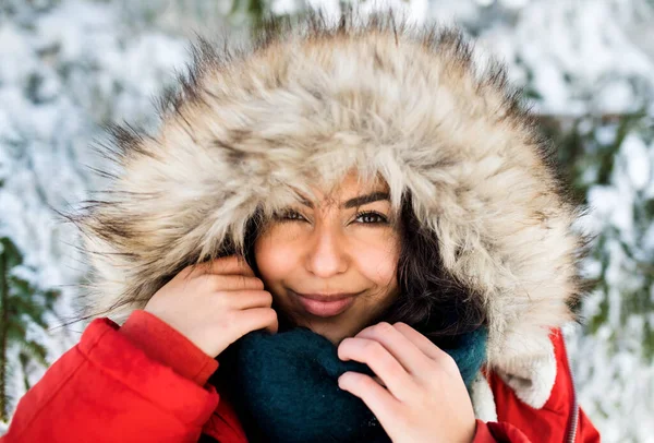 A front view portrait of young woman standing outdoors in snowy winter forest. — Stock Photo, Image
