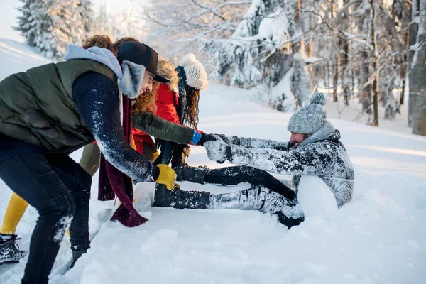 En grupp unga vänner på en promenad utomhus i snö i vinterskogen. — Stockfoto