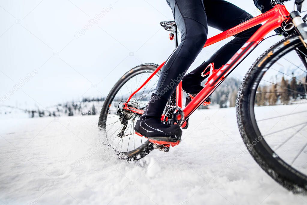 Midsection of mountain biker riding in snow outdoors in winter.