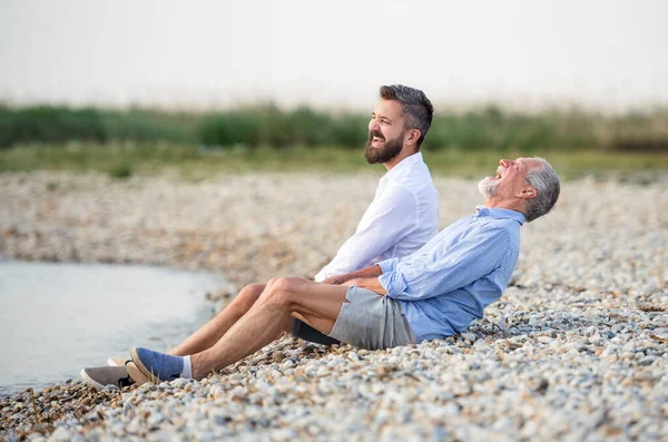 Старший отец и зрелый сын сидят у озера. Копирование пространства . — стоковое фото