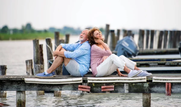 Oudere echtparen op vakantie achterover leunend bij het meer. — Stockfoto