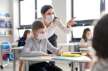 Yüzü maskeli öğretmen ve çocuklar 19 numaralı karantina ve tecritten sonra okula geri döndüler..