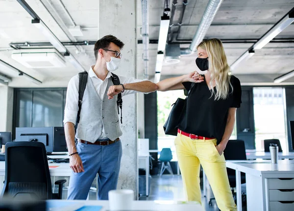 Young people with face masks back at work in office after lockdown, greeting. — Stock Photo, Image