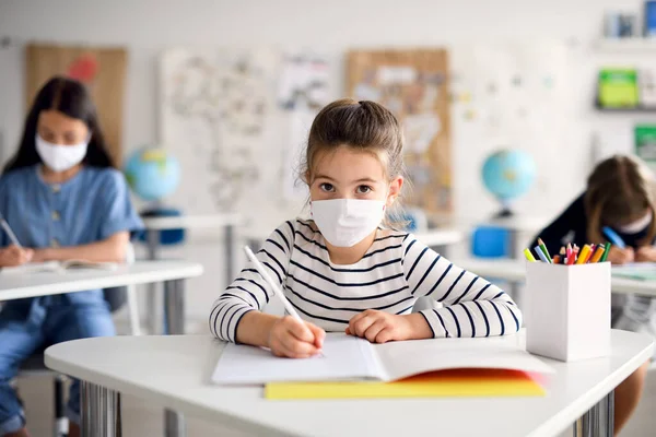 Niño con mascarilla en la escuela después de covid-19 cuarentena y encierro, escritura . — Foto de Stock