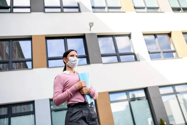 Low angle view of teacher with face mask after lockdown, walking in front of school. — Stock Photo, Image
