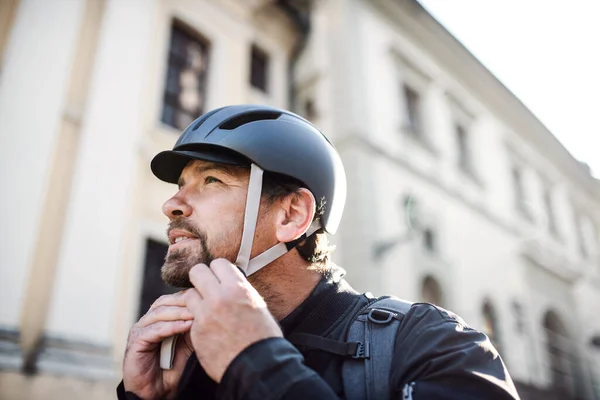 Homem de entrega mensageiro de fixação capacete de bicicleta na cidade . — Fotografia de Stock