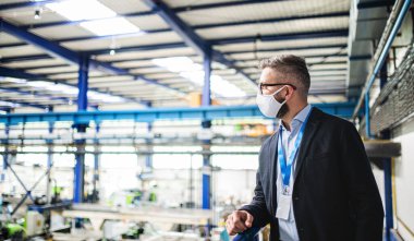 Endüstriyel fabrikada duran koruyucu maskeli teknisyen veya mühendis.