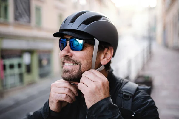 Entrega hombre mensajero sujeción casco de bicicleta y gafas de sol en la ciudad . —  Fotos de Stock