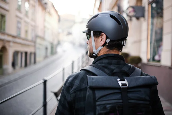 Visão traseira do mensageiro entregador com mochila e capacete de bicicleta na cidade . — Fotografia de Stock