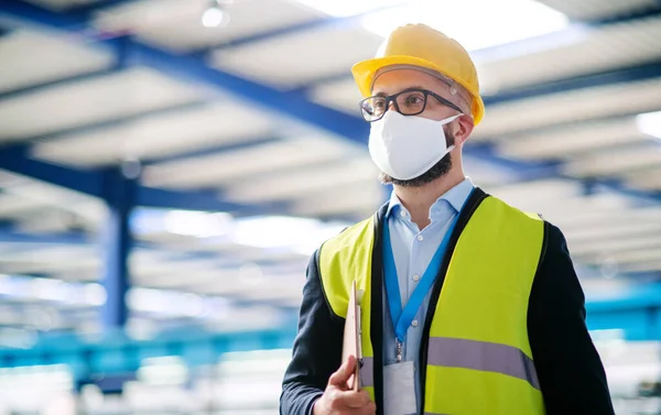 Technik nebo inženýr s ochrannou maskou a helmou stojící v průmyslové továrně. — Stock fotografie