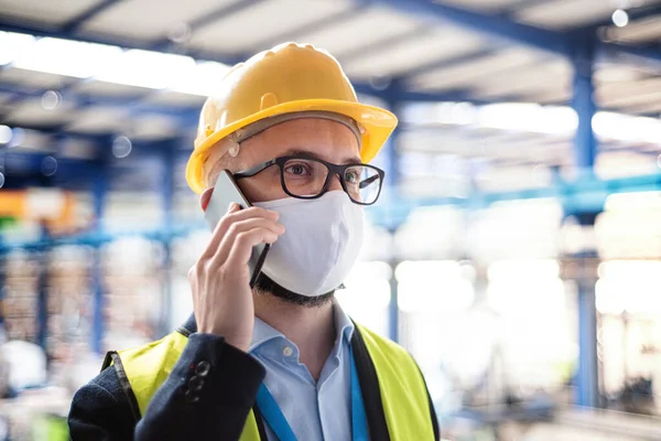 Technik nebo inženýr s ochrannou maskou a telefonem v průmyslové továrně. — Stock fotografie