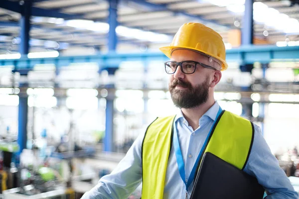 Технік або інженер з шоломом, що стоїть на промисловому заводі . — стокове фото