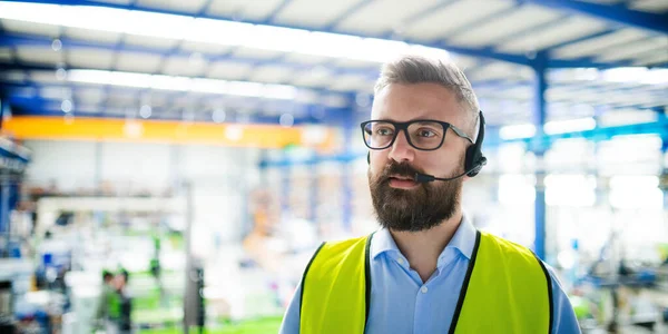 Técnico ou engenheiro com máscara protetora e fone de ouvido trabalhando na fábrica industrial . — Fotografia de Stock