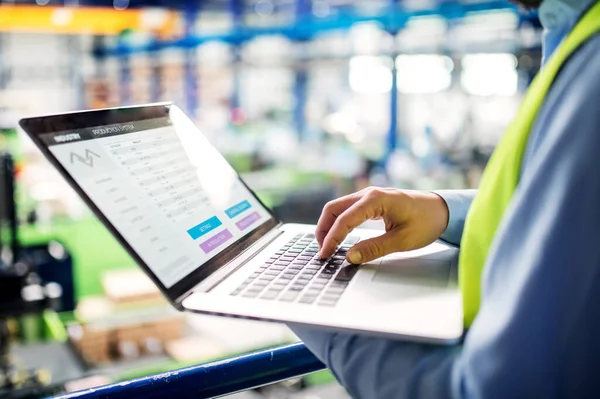 Neznámý technik nebo inženýr s notebookem stojící v průmyslové továrně. — Stock fotografie