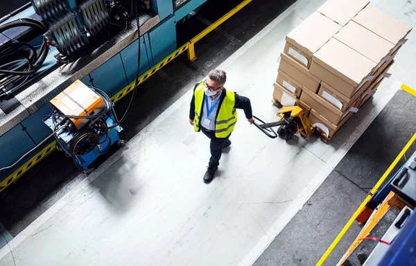 Luchtfoto van een werknemer met een beschermend masker die in een industriële fabriek of magazijn werkt. — Stockfoto