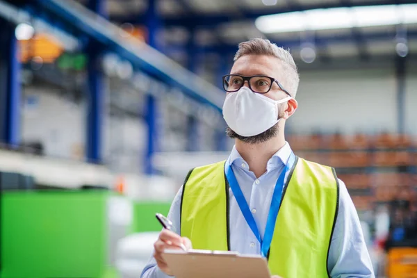 Technicien ou ingénieur avec masque de protection travaillant dans une usine industrielle, marchant . — Photo