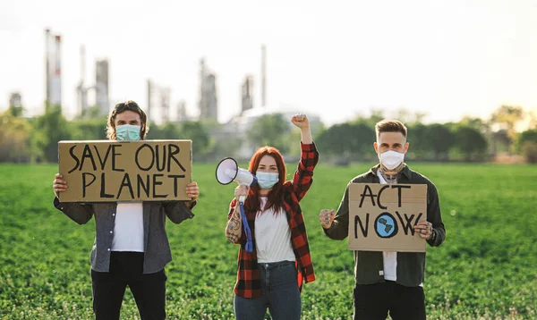 Gruppo di giovani attivisti con cartelli in piedi all'aperto vicino alla raffineria di petrolio, protestando . — Foto Stock