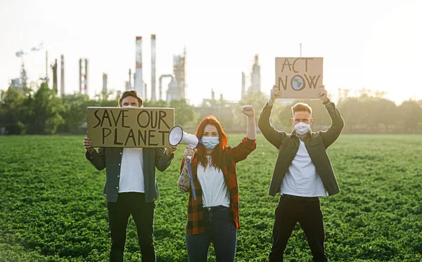 Grupo de jovens ativistas com cartazes em pé ao ar livre pela refinaria de petróleo, protestando . — Fotografia de Stock