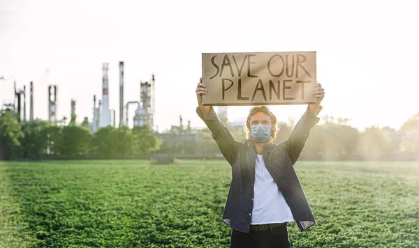 Jovem ativista com cartaz em pé ao ar livre pela refinaria de petróleo, protestando . — Fotografia de Stock