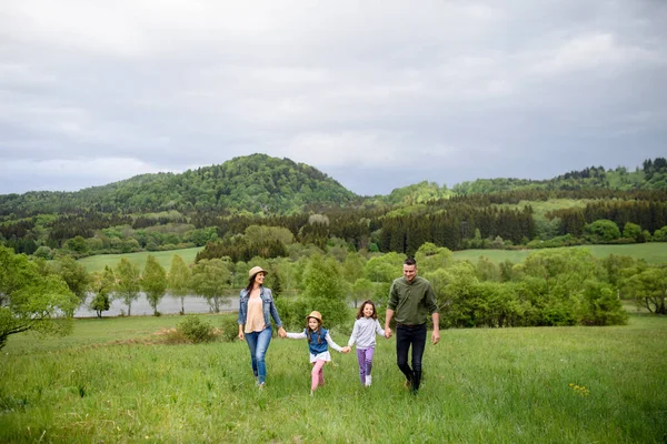 Lycklig familj med två små döttrar som vandrar utomhus i vårnaturen. — Stockfoto