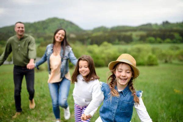 Familia feliz con dos hijas pequeñas corriendo al aire libre en la naturaleza de primavera . — Foto de Stock