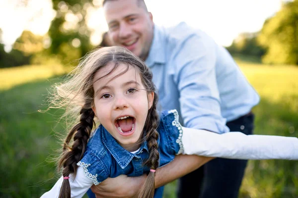 Otec si hraje s malou dcerou venku v jarní přírodě, baví se. — Stock fotografie