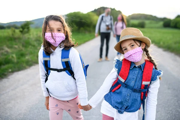 Família com duas filhas pequenas em viagem ao ar livre na natureza, usando máscaras faciais . — Fotografia de Stock